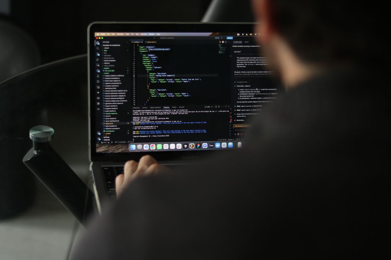 Services A focused developer writing code on a laptop in an indoor workspace.